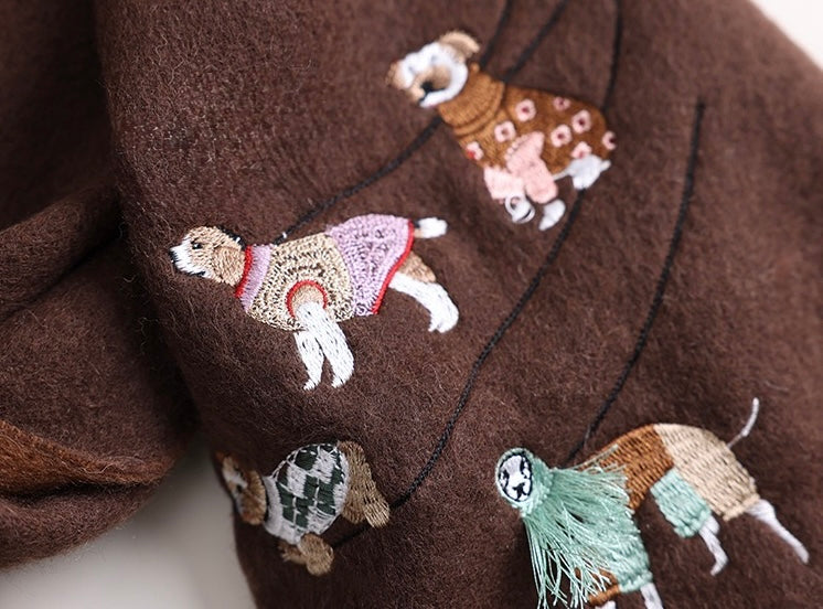 Brown wool blanket with embroidered designs draped over a wooden chair.