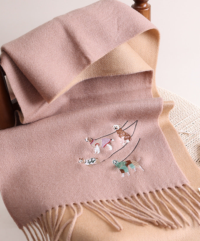 Pink wool blanket with embroidered designs draped over a wooden chair.