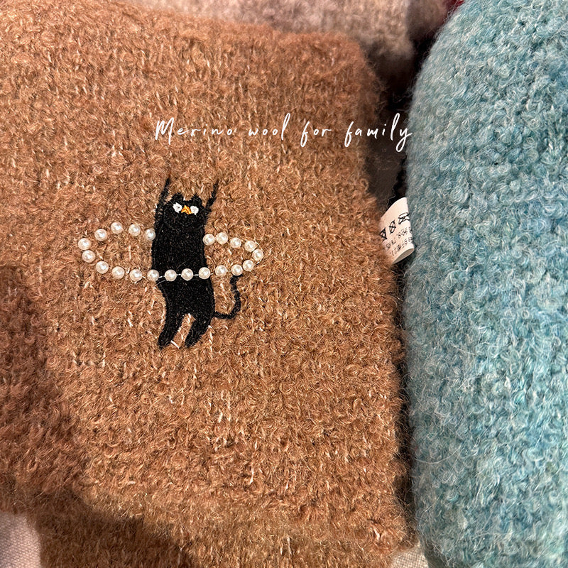 Brown yarn with a black cat and pearl design, next to blue yarn.